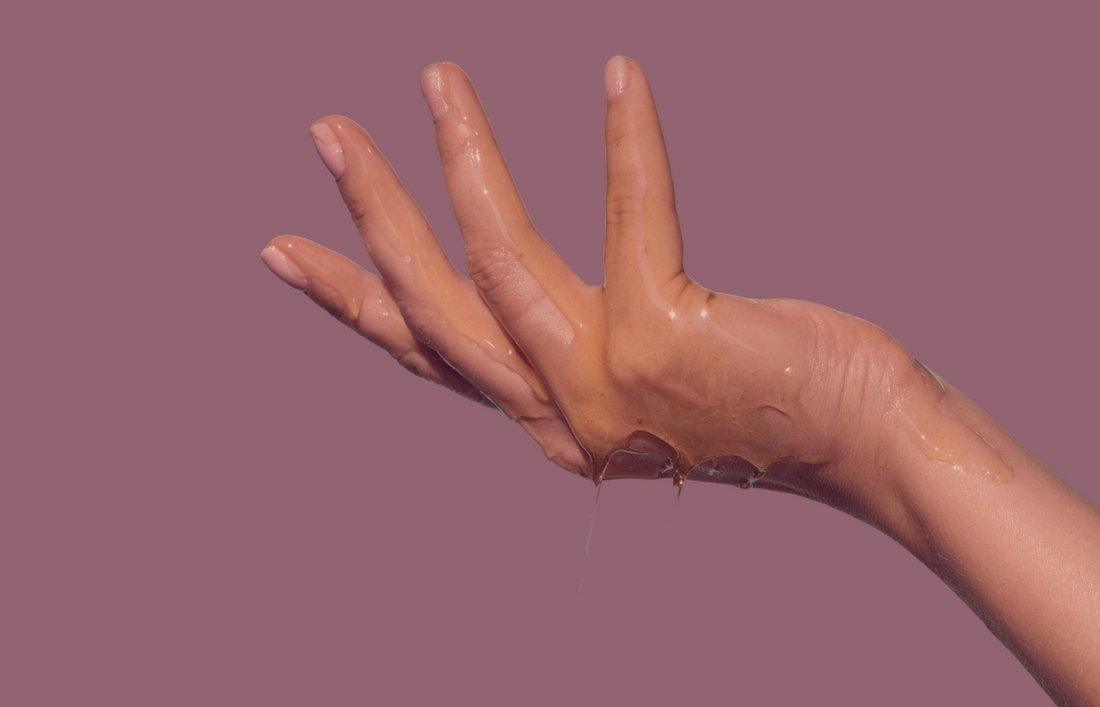 Hand covered in lube with pink background
